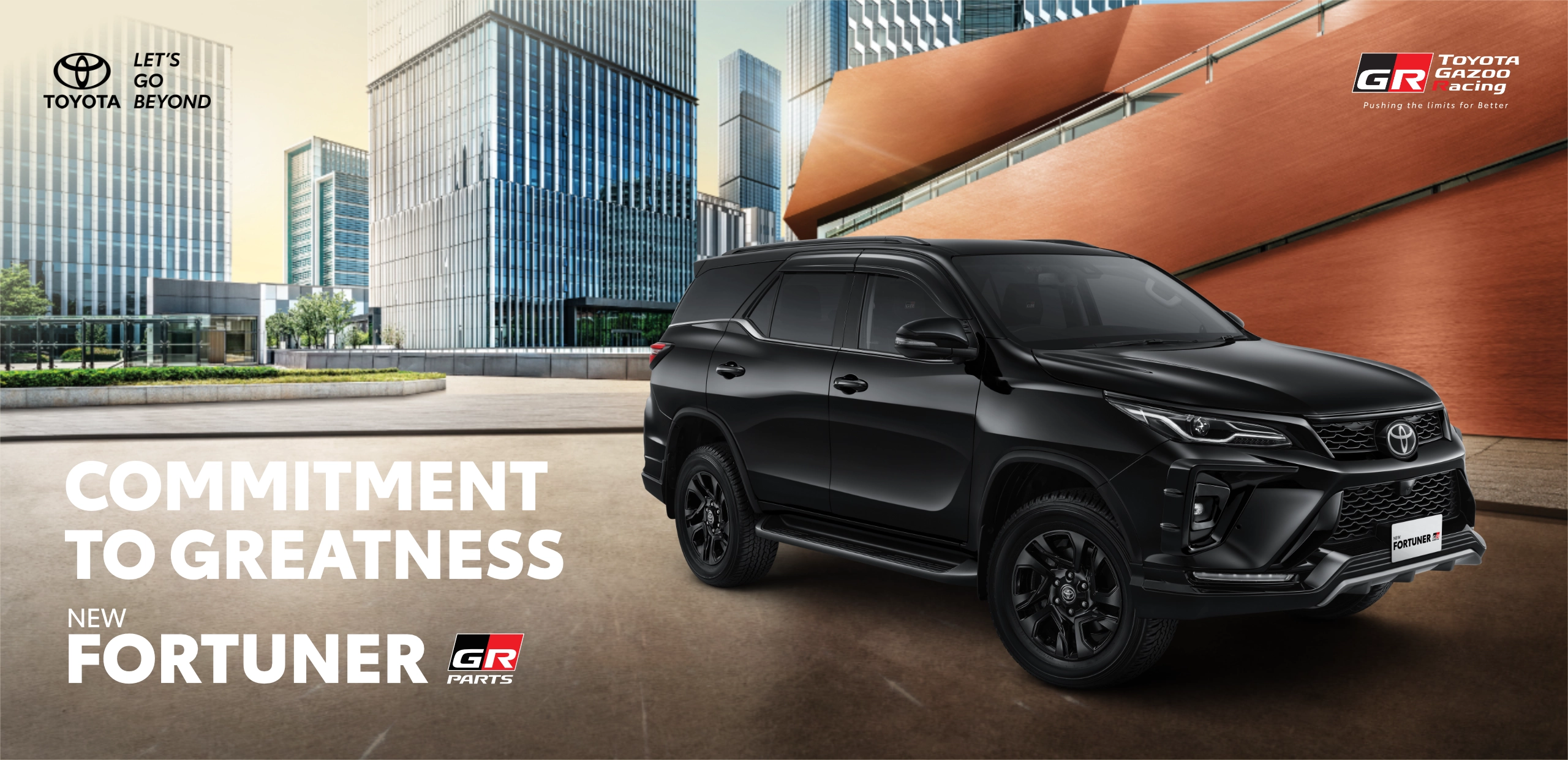 Banner promosi Toyota New Fortuner GR Parts warna hitam yang terparkir gagah di kawasan perkotaan berarsitektur modern, memuat tagline utama Commitment to Greatness dan logo Toyota Gazoo Racing.
