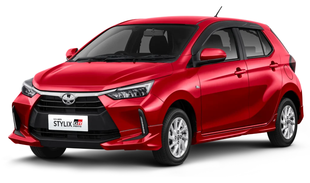 Mobil Toyota New Agya Stylix warna merah dengan tambahan aksesoris GR Parts, menampilkan desain hatchback yang sporty dan modern dari sudut depan samping.