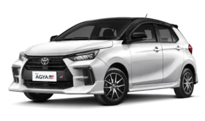 Tampilan studio tampak depan samping (3/4) mobil hatchback kompak Toyota New Agya GR Sport warna putih dengan atap dan spion berwarna hitam (two-tone). Mobil ini memiliki latar belakang hitam pekat yang menonjolkan body kit agresif, gril dengan emblem GR, dan velg alloy sporty. Gambar produk utama resmi dari Tunas Toyota