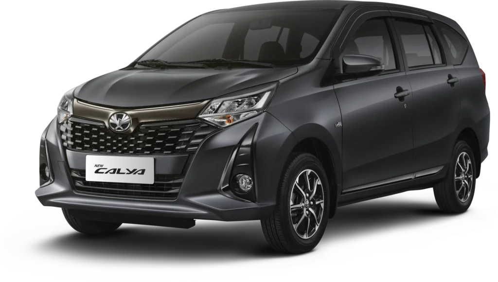Mobil Toyota New Calya varian warna abu-abu gelap (Grey Metallic), tampak serong depan menonjolkan desain grille elegan bernuansa dark chrome dan headlamp modern berlatar belakang hitam pekat.