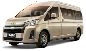 Mobil van komersial kelas premium Toyota New Hiace Premio varian warna beige, tampak serong depan menonjolkan desain semi-bonnet yang modern, kabin eksklusif, dan bodi elegan berlatar belakang hitam pekat.
