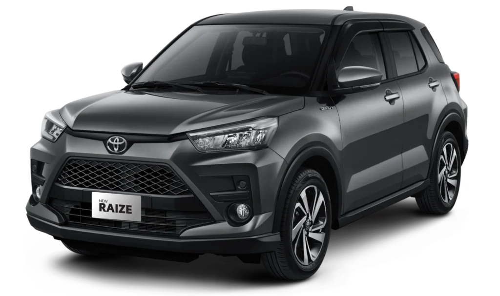 Tampilan studio tampak depan samping (3/4) mobil compact SUV Toyota New Raize tipe G Turbo warna abu-abu metalik (Gray Metallic) dengan latar belakang hitam. Mobil ini memiliki gril depan trapesium lebar, emblem turbo di bagian fender, dan velg alloy berdesain kipas dua warna (two-tone machining). Gambar produk Tunas Toyota.