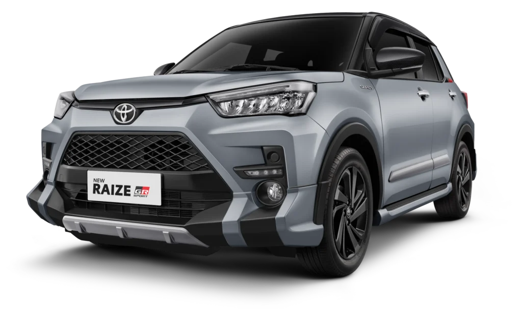 Tampilan studio tampak depan samping (3/4) mobil SUV kompak Toyota New Raize GR Sport warna silver dengan atap dan spion berwarna hitam (two-tone). Mobil ini berlatar belakang hitam pekat yang menonjolkan desain gril depan agresif, body kit aerodinamis GR Sport, lampu depan LED, serta velg alloy berwarna hitam. Gambar produk utama resmi dari Tunas Toyota.