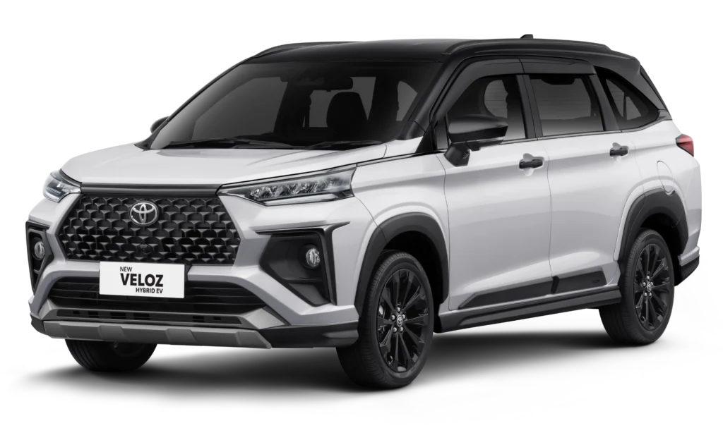 Mobil Toyota New Veloz Hybrid EV varian warna dual tone putih dengan atap hitam, tampak serong depan menonjolkan desain grille modern, velg alloy hitam, dan bodi premium berlatar belakang hitam pekat.