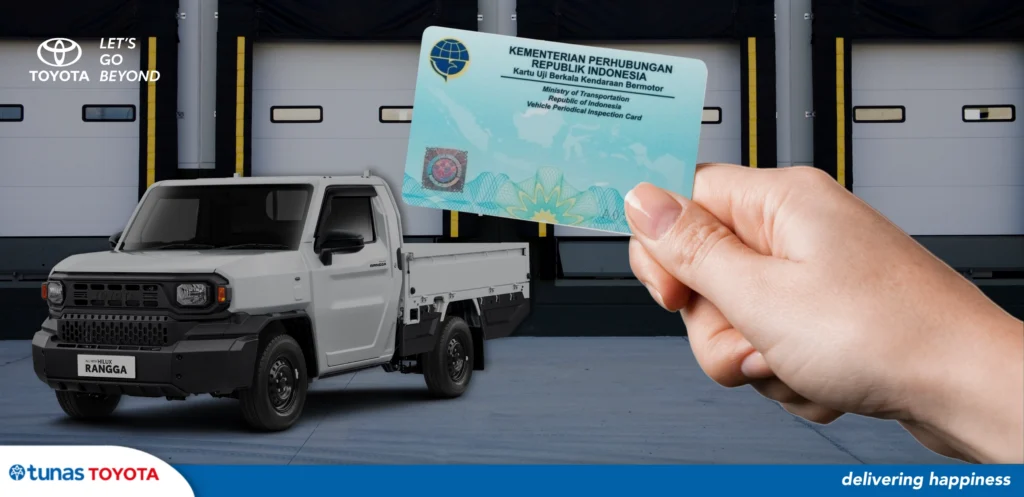 Banner sampul artikel Tunas Toyota menampilkan tangan yang memegang Kartu Uji Berkala Kendaraan Bermotor (KIR) dari Kementerian Perhubungan, dengan latar belakang mobil pikap komersial Toyota Hilux Rangga berwarna putih di area pergudangan.