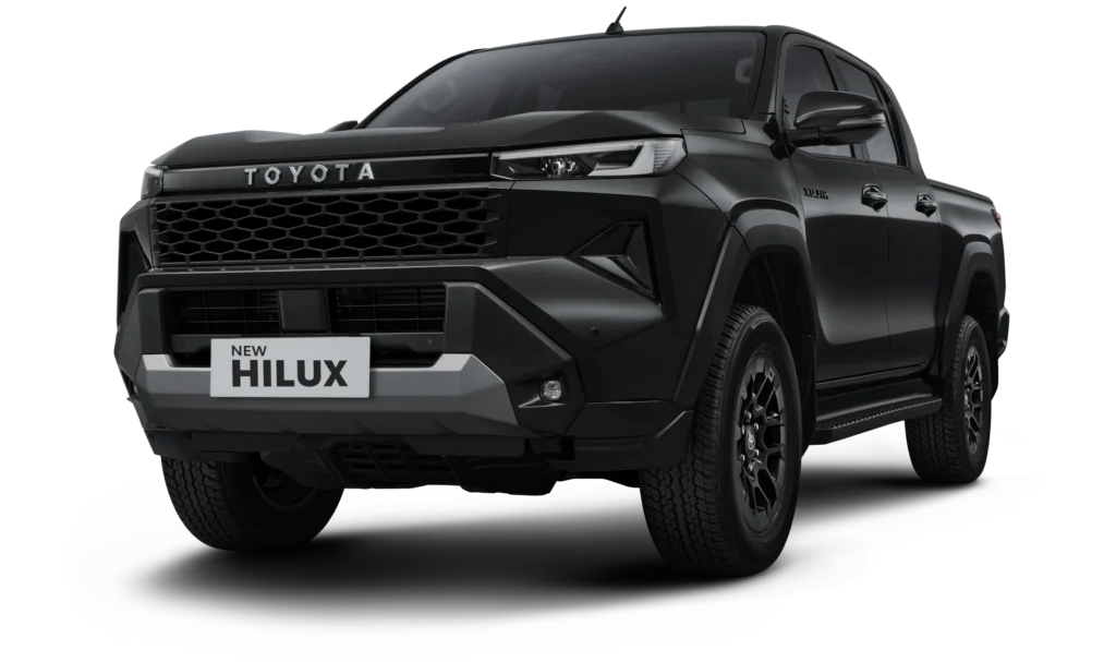 Mobil pikap kabin ganda Toyota New Hilux Double Cabin varian Tipe G 4x4 transmisi manual warna hitam, tampak serong depan menonjolkan desain maskulin berlatar belakang hitam pekat.