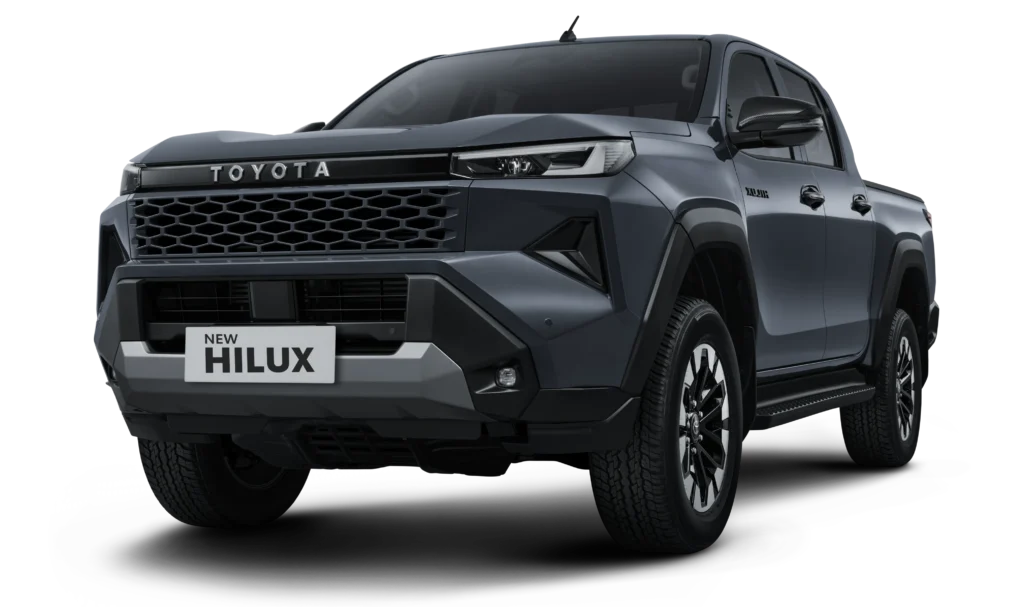Mobil pikap kabin ganda Toyota New Hilux Double Cabin varian tertinggi Tipe V 4x4 transmisi otomatis warna abu-abu, tampak serong depan menonjolkan desain premium berlatar belakang hitam pekat.